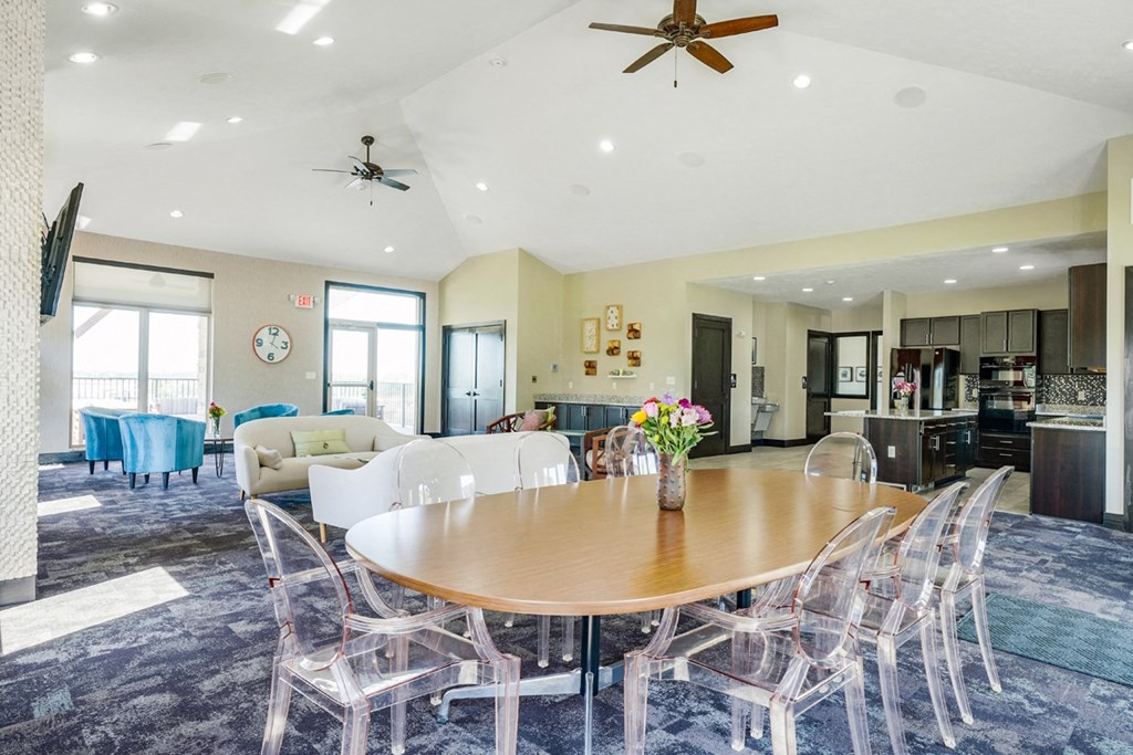 a dining area with a table and chairs and a kitchen in the background