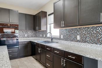 clubhouse kitchen with dark cabinets and granite countertops