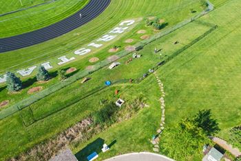 grassy area with fenced dog park and running track in background