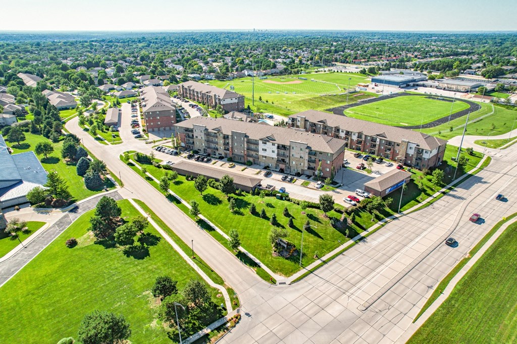 an aerial view of a large apartment complex with green fields in the background