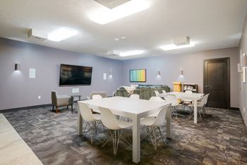 a theater room with a sectional couch, a large flat screen TV, and table seating in the back