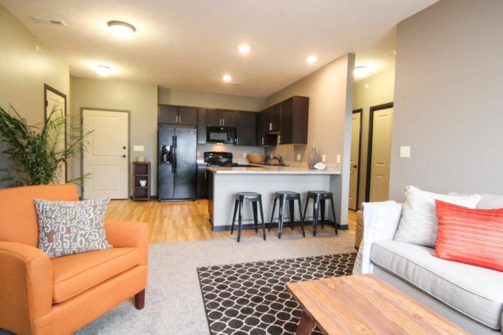 A living room with a couch, chair, and a bar area.