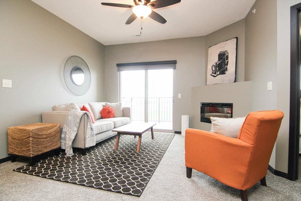 A living room with a white couch, a black and white rug, and an orange chair.
