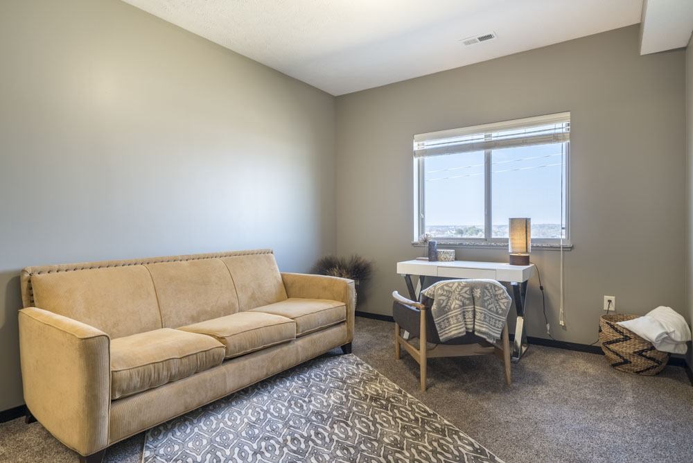A tan couch sits in a room with a table and chairs.