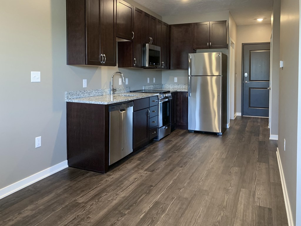 Kitchen with dark brown cabinets and matching stainless steel appliances in a studio apartment at the flats at shadow creek