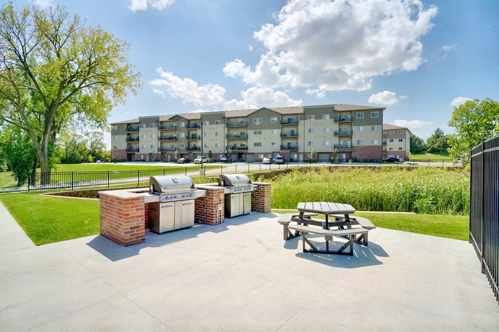 Outdoor grilling area with two stainless steel grills and a round picnic table