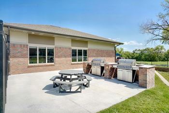 Outdoor grilling area with two stainless steel grills and a round picnic table