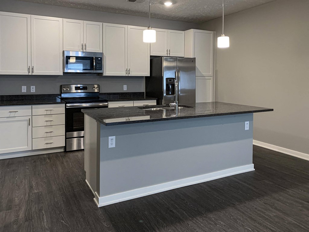 Spacious kitchen with white cabinets and large floating island with granite countertops