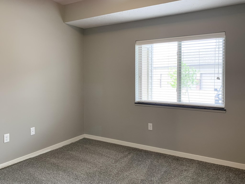 Large carpeted bedroom with window The Flats at Shadow Creek in Lincoln Nebraska
