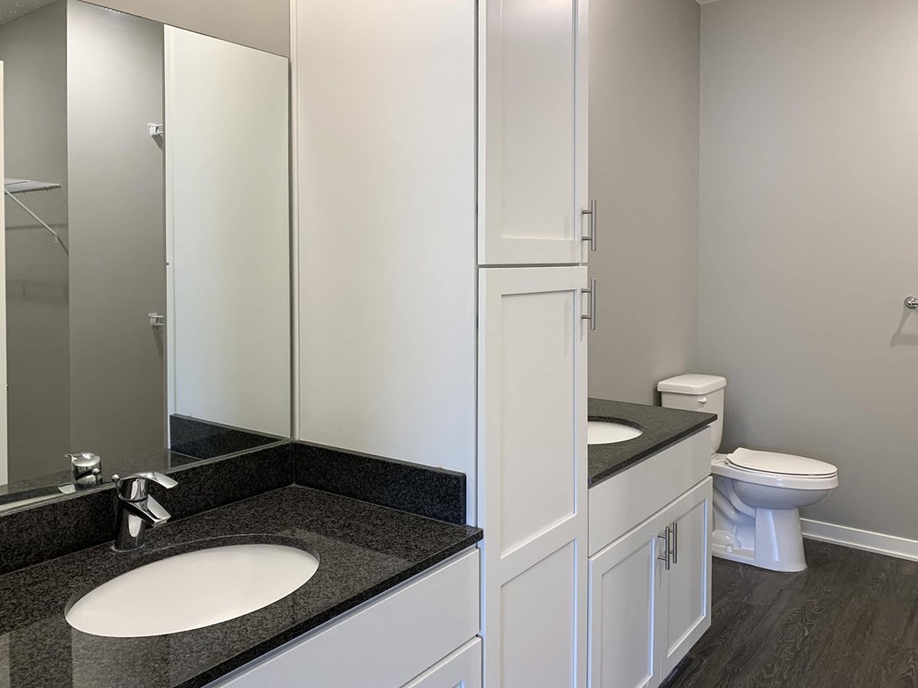 A bathroom with a sink, toilet, and a mirror.