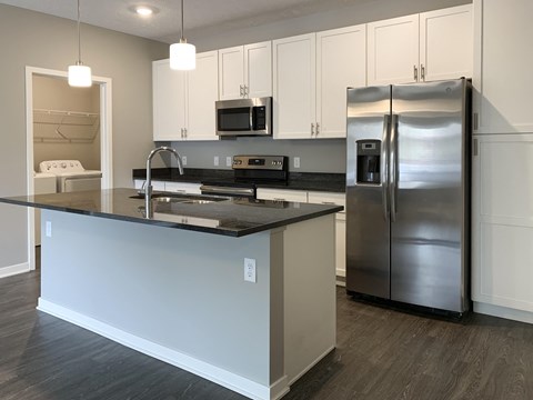 a kitchen with a island and a stainless steel refrigerator