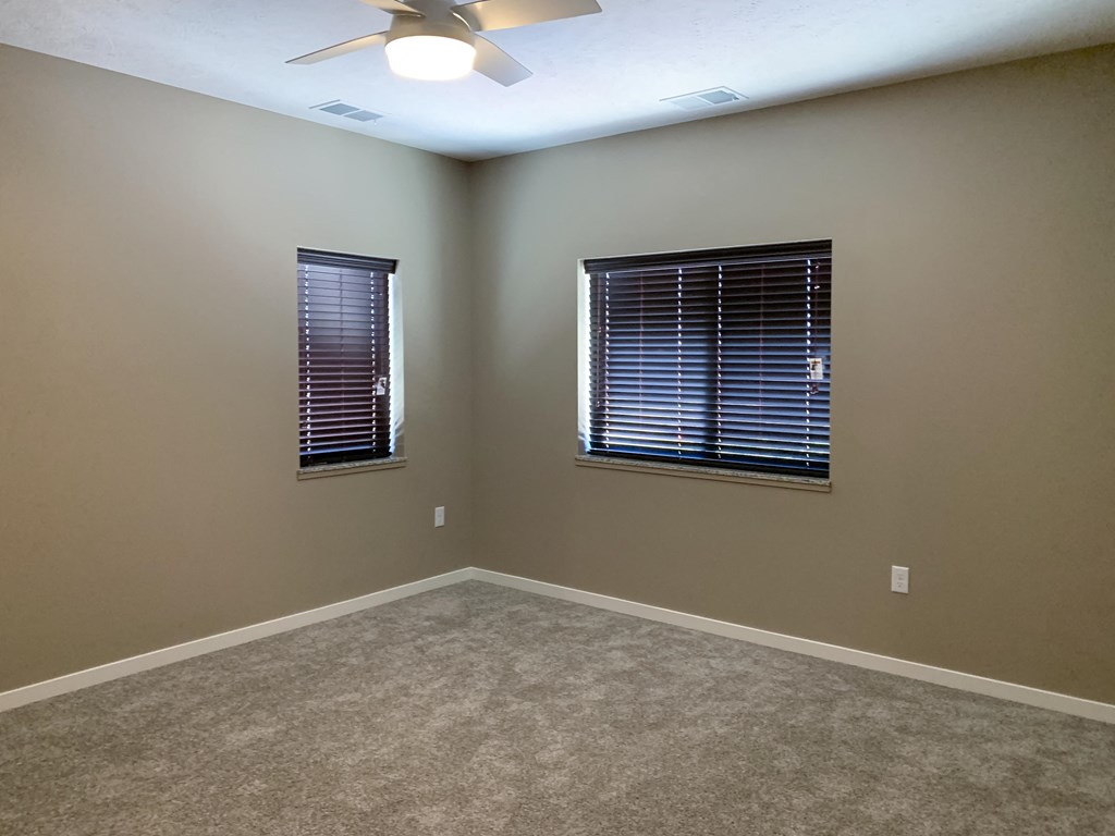 Carpeted bedroom with two windows on either wall