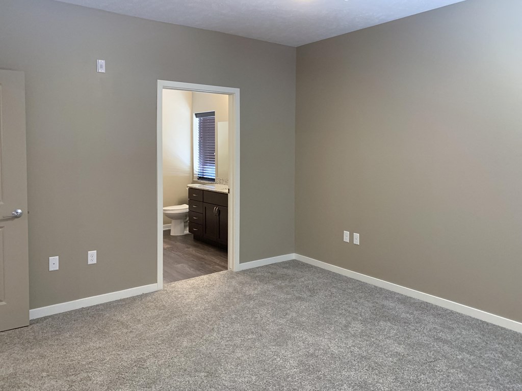 carpeted bedroom with private master bathroom