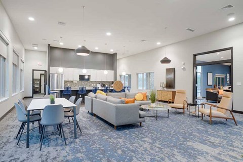 A spacious living room with a grey sofa set and a dining table with chairs.