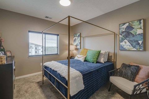 a bedroom with a bed and a chair and a window