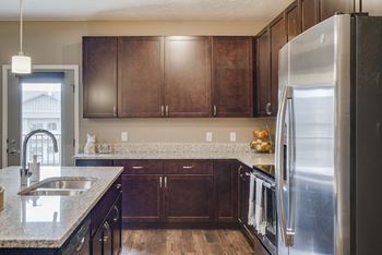 Kitchen with warm dark brown cabinets, hardwood floors, and stainless steel appliances