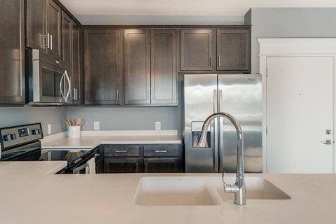A modern kitchen with dark brown cabinets and stainless steel appliances.