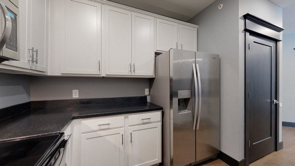 a kitchen with white cabinets and a stainless steel refrigerator