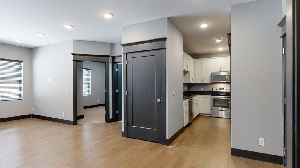 a kitchen and living room with a hardwood floor and grey walls