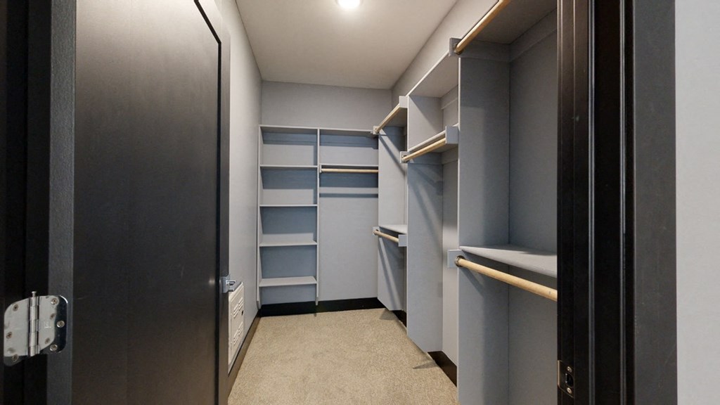 a walk in closet with gray walls and shelves