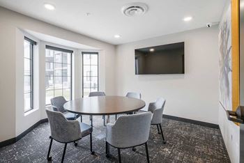 The business conference room featuring a table with chairs and a tv