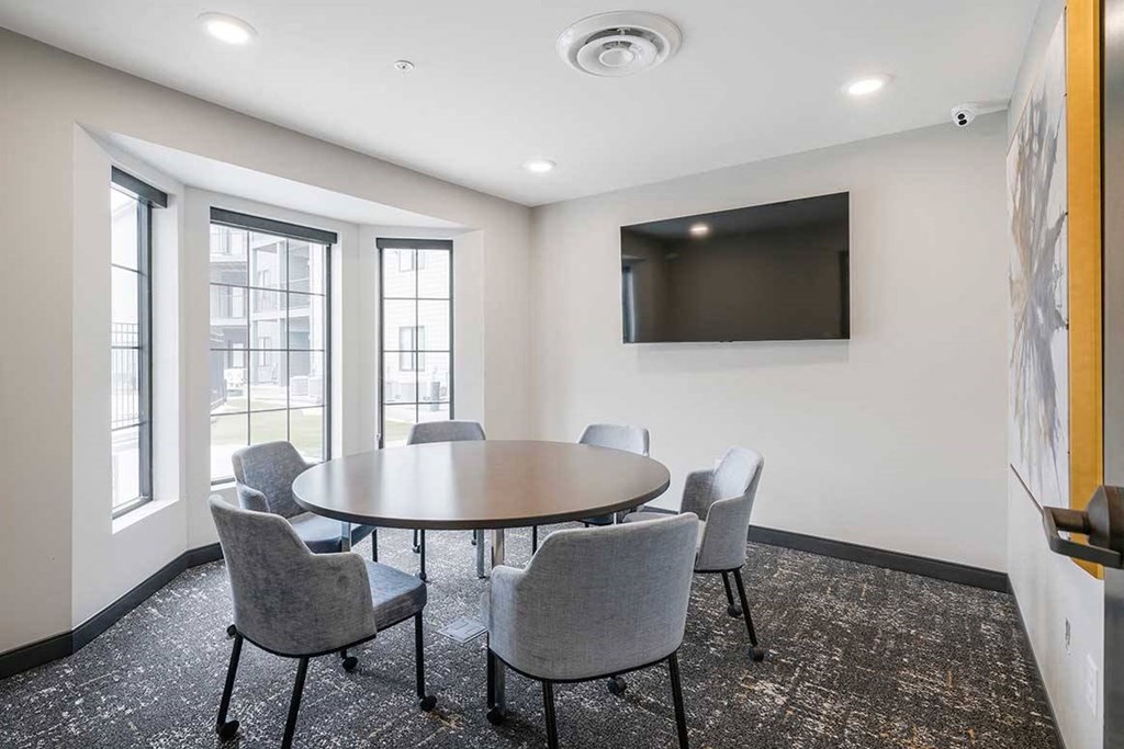 The business conference room featuring a table with chairs and a tv