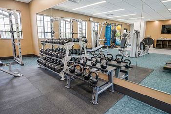 a fitness center tith two racks of free weights in front of a mirrored wall