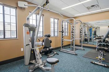 a fitness center with an exercise machine and a free weight bar rack