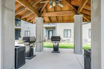 a covered outdoor grill station with two grills and a ceiling fan