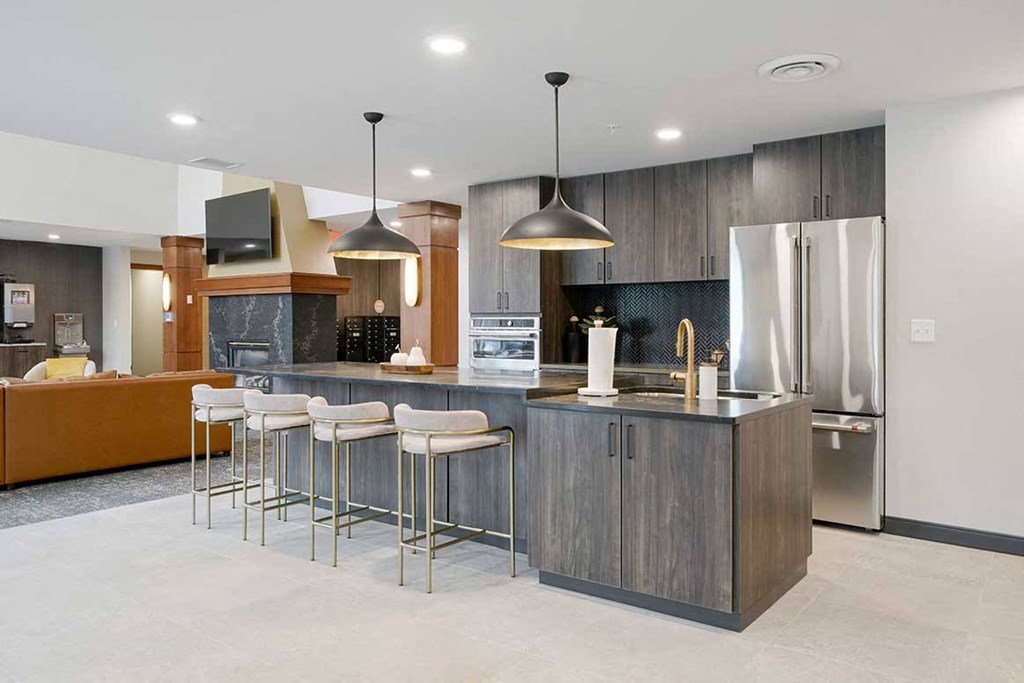 The clubhouse kitchen featuring dark cabinets, stainless steel appliances, and a large island