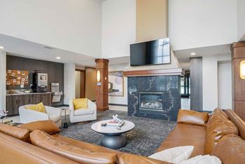 The clubhouse lounge featuring a 2-way fireplace, coffee bar, tv, and lounge seating.