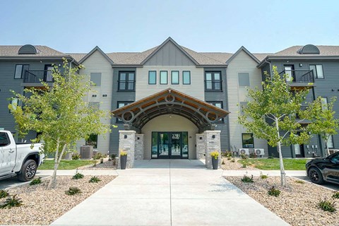 the front entrance of The Knock Apartments in Lincoln, NE with a walkway and trees