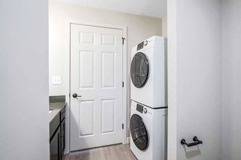 a stacked washer and dryer across from the bathroom vanity sink