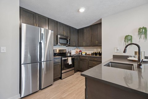 A modern kitchen with a stainless steel refrigerator and wooden cabinets.