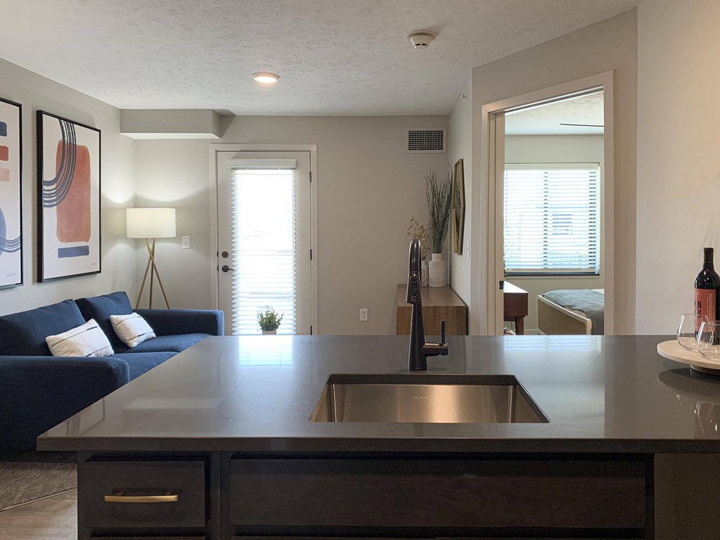 a kitchen with a sink and a couch in the background