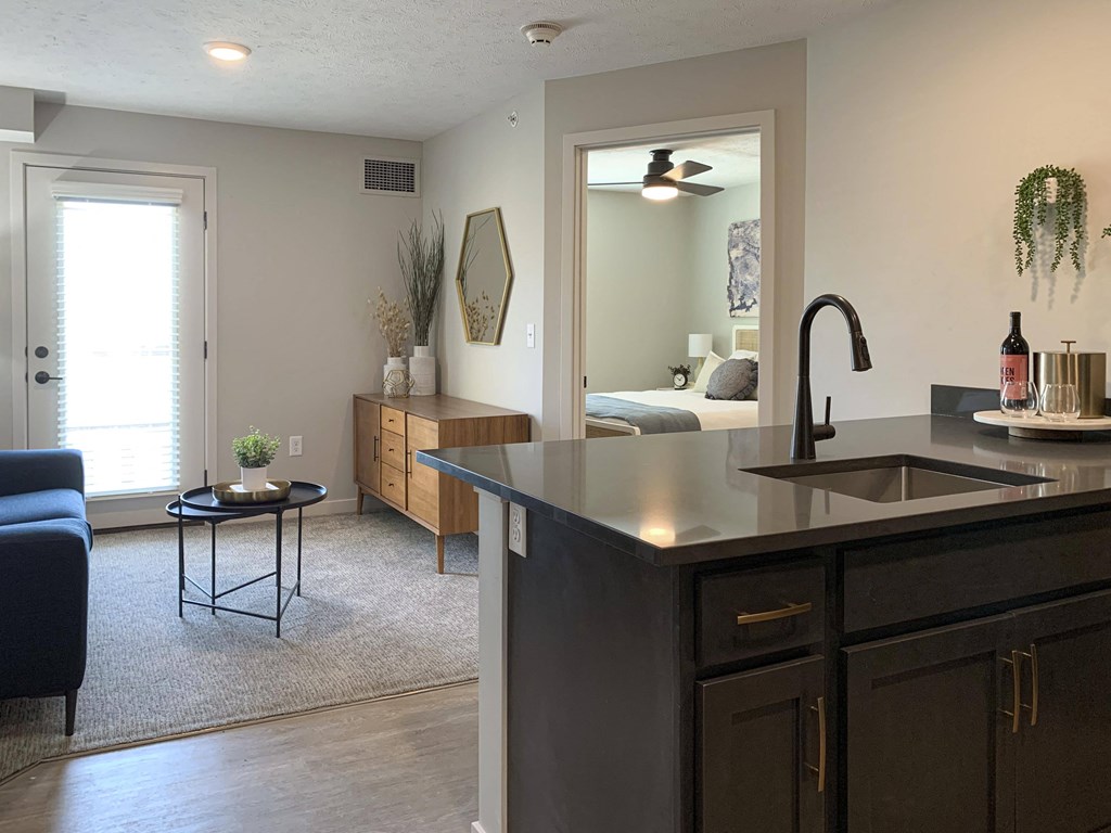 a kitchen with an island and a living room in the background