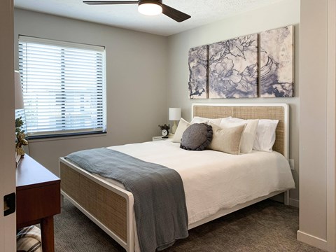 Furnished bedroom with ceiling fan and marbled art above the bed