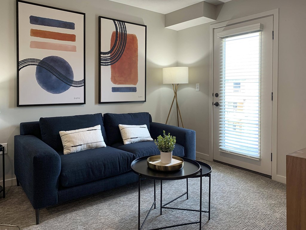 a living room with a blue couch and two paintings on the wall