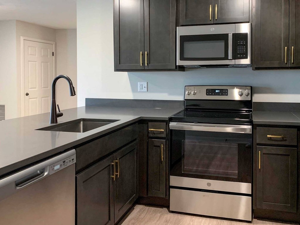 a kitchen with dark cabinets and stainless steel appliances
