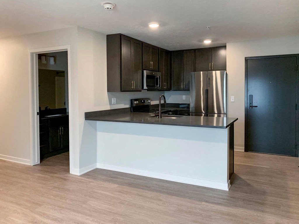 a kitchen with dark cabinets and counter tops and stainless steel appliances