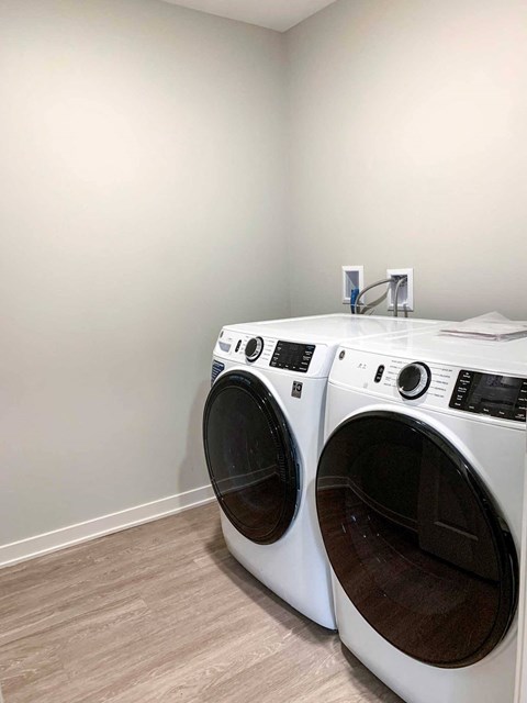 a washer and dryer in a laundry room with a wooden floor