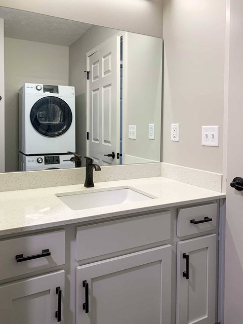 a bathroom with a sink, cabinets, and a stackable washer and dryer