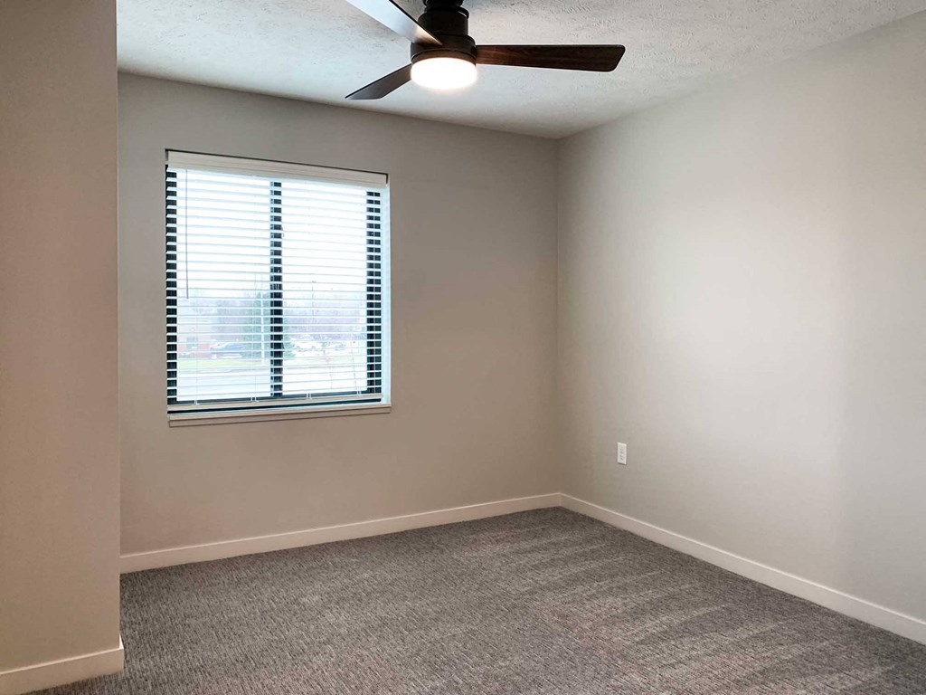 a bedroom with a ceiling fan and window