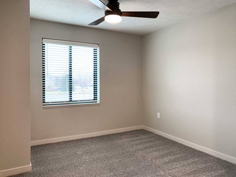 a bedroom with a ceiling fan and window