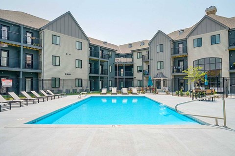 a resort style swimming pool with lounge charge surrounding it, in the center of an apartment courtyard