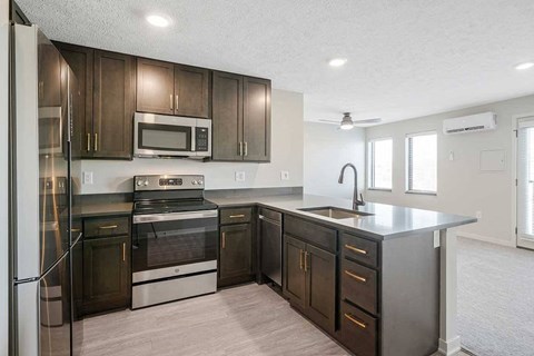 A kitchen with stainless steel appliances and dark cabinets