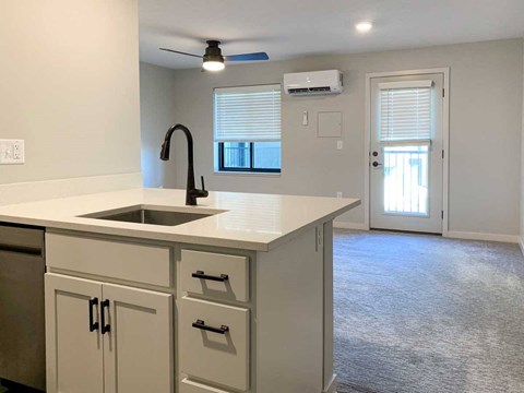 a kitchen peninsula with white quartz countertops and white cabinets