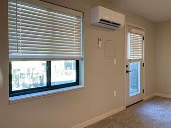 a living room with a window, air conditioner, and a door to a balcony