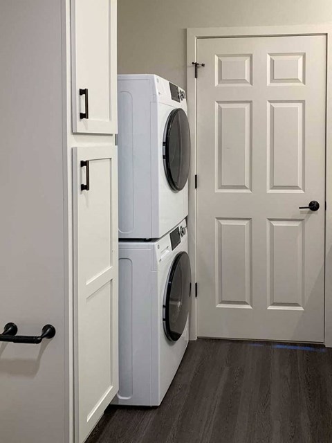 a bathroom with a linen storage cabnet and a stackable washer and dryer