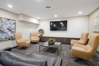 The theater room with a couch, armchairs, and a tv